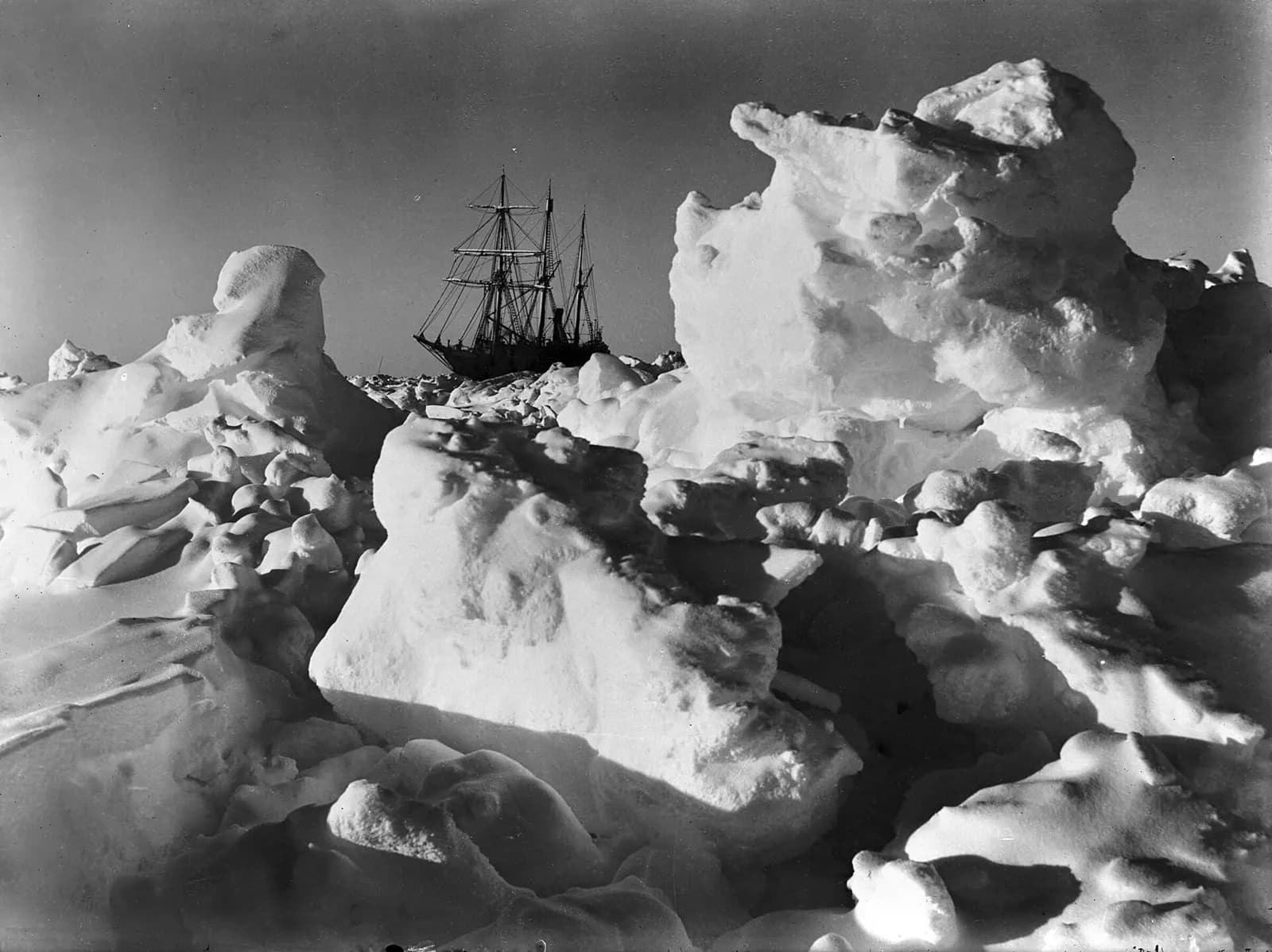 Black-and-white photograph of the three-masted ship Endurance held fast behind towering ridges of pack ice.
