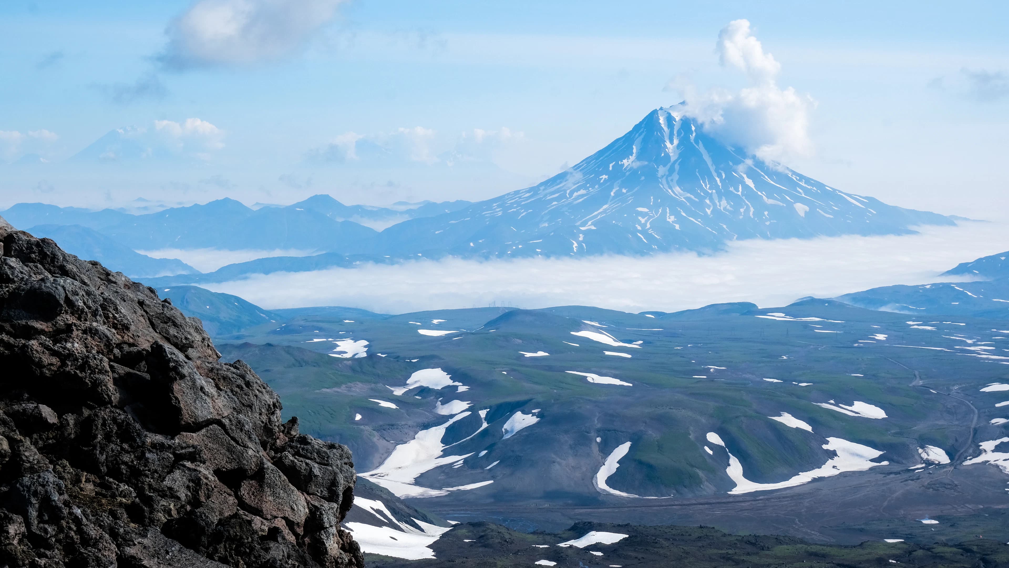 Snow-covered volcanic terrain beneath low cloud; representative route imagery.