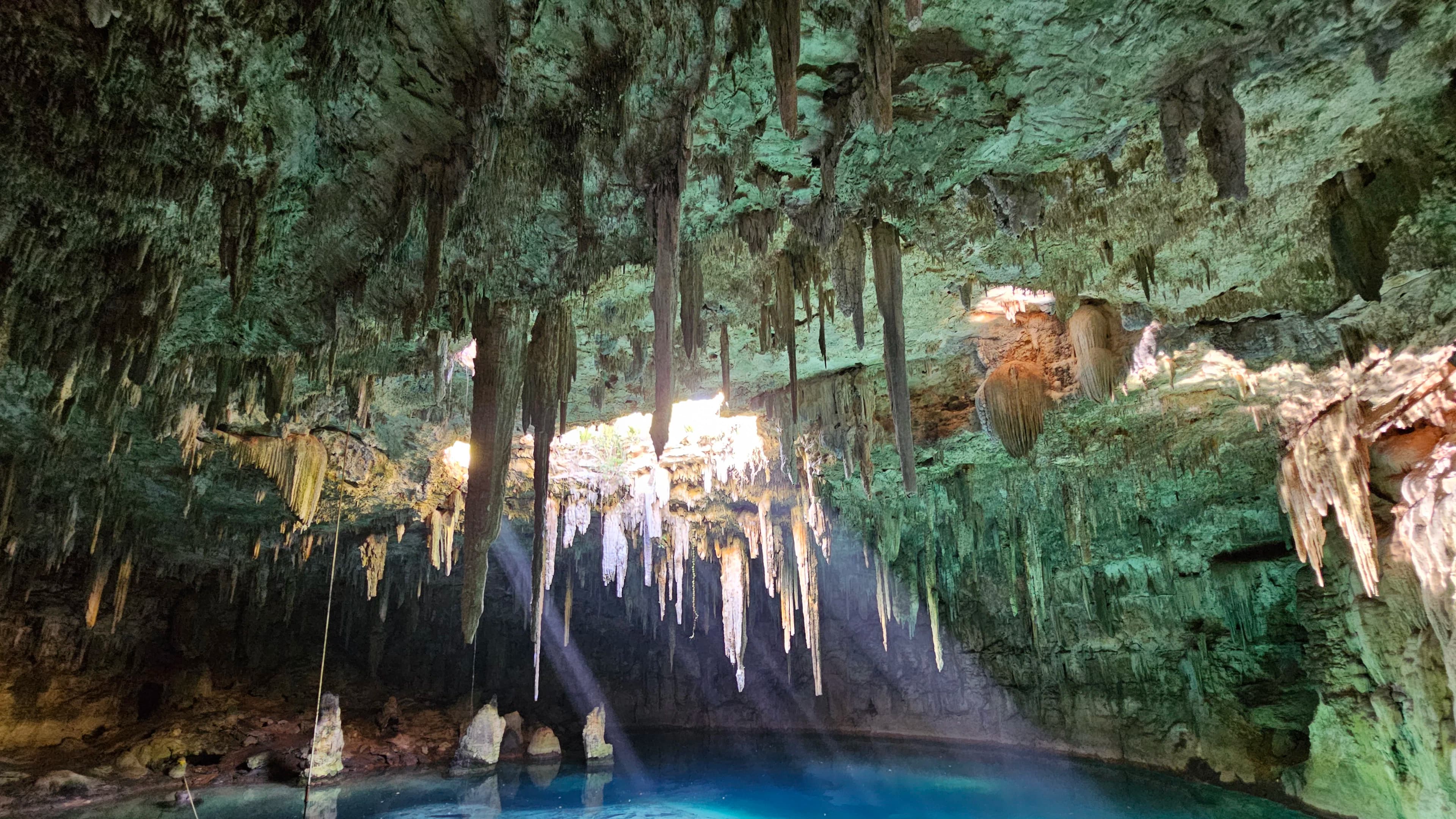 A clear blue cenote framed by limestone and tropical forest in Mexico.